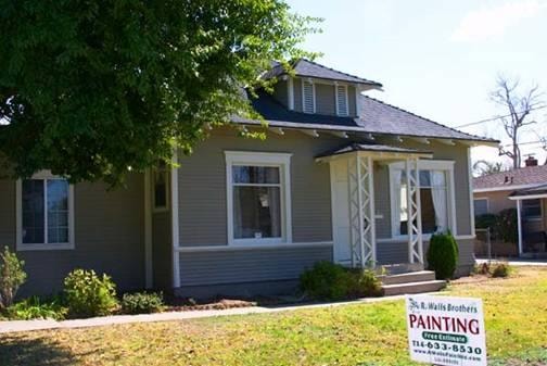 Freshly painted craftsman-style residential home with R Walls Painting sign on the front lawn